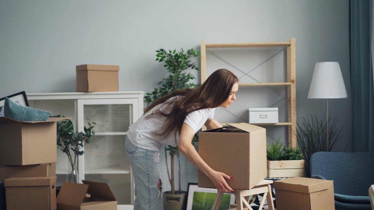 services-02 A young woman with long hair arranging boxes in her new home. Ideal for moving and lifestyle stories.